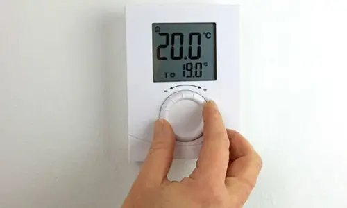 04 Close-up de una mano ajustando un termostato digital Termostato señalando 20 grados